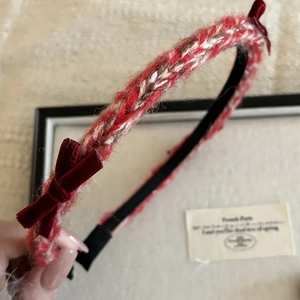 Detail of red and white knitted headband featuring plush dark red velvet side bows