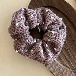 Chic dusty pink knitted scrunchie with white polka dot accents on a wooden tray