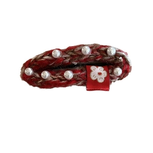 Knitted red hair clip with white pearls and a floral label on a white background
