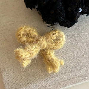 Barrette à cheveux nœud en tricot jaune fait main avec paillettes noires sur fond de livre