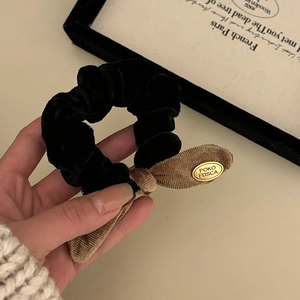 Elegant velvet scrunchie with corduroy bow and gold label for bun hairstyle