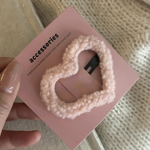 Macro view of pink heart hair clip with soft lamb wool texture on branded card