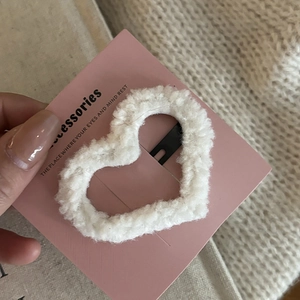 Close-up of white plush heart hair clip with lamb wool texture on pink card
