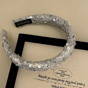 Close-up of sparkling sequins on grey velvet headband with a handmade label detail