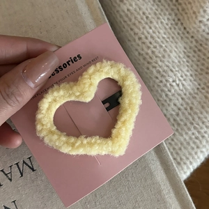 Close-up of cream fuzzy heart hair clip with cozy sherpa texture on pink display card