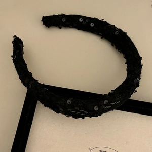 Detail of a vintage black velvet headband with shimmering sequins on a luxury tray