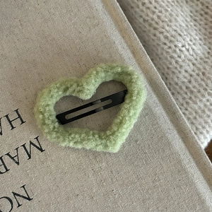 Close-up of heart-shaped light green faux shearling hair clip with black metal BB clip