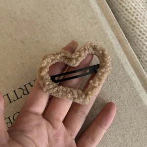 Detail view of a brown plush heart hair clip with soft lamb wool texture on burlap