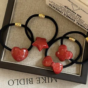 Close-up of red glitter hair ties featuring heart, star, and bow shapes on black elastic