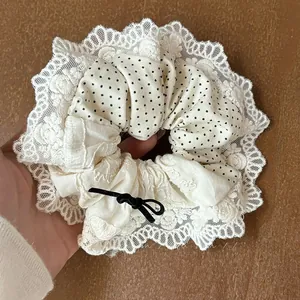 Close-up of a large lace scrunchie with black polka dots and a chic ribbon bow tie