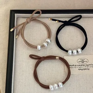 Détail de trois chouchous à perles avec double fil élastique en beige, noir et marron