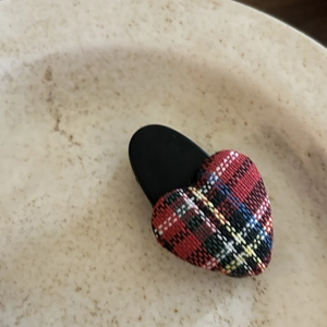 Detail of a red plaid heart hair clip featuring a classic tartan fabric on a black base