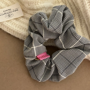 Classic black and white checkered fabric scrunchie with pink woven label for hair styling