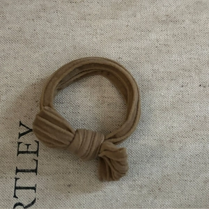 Élastique à cheveux en tissu kaki avec nœud papillon sur fond texturé en lin