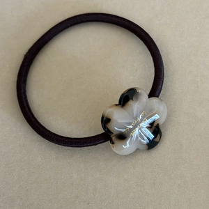 Detail of tortoiseshell acetate flower charm with gold La France lettering on hair tie