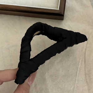 Detail view of large triangle hair claw clip wrapped in black pleated fabric