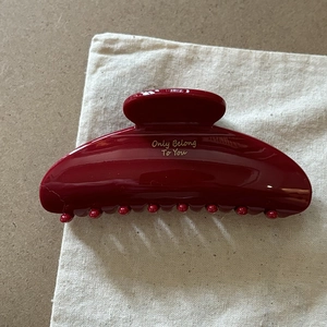 Dettaglio di una grande pinza per capelli bordeaux con testo dorato Only Belong To You