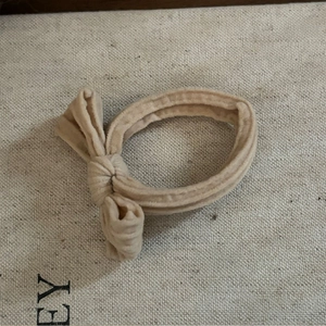 Élastique à cheveux beige avec nœud et texture côtelée pour queue de cheval durable