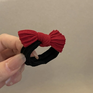 Élastique à cheveux élégant avec nœud en velours côtelé rouge tenu à la main