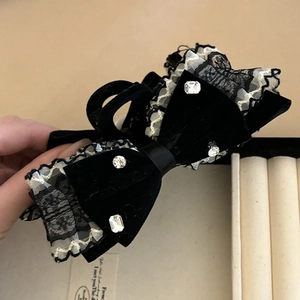 Detailed macro view of black velvet bow hair claw with lace edges and crystal accents
