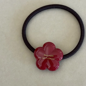 Detail of red acetate flower hair tie with golden Barrette La France text engraving