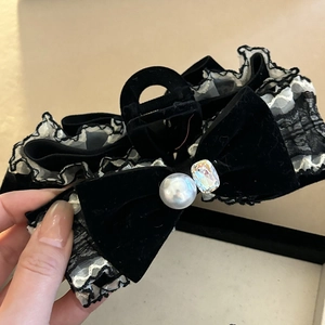 Detail of elegant black lace bow hair claw with faux pearl and emerald cut crystal