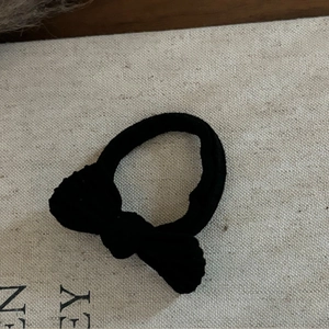 Gros plan d'un élastique à cheveux avec nœud noir sur fond de toile montrant la texture