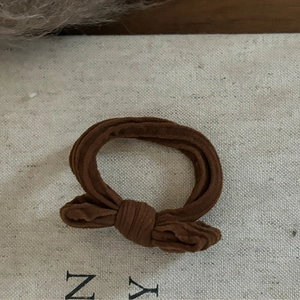 Gros plan d'un chouchou marron en velours côtelé avec nœud sur une toile texturée