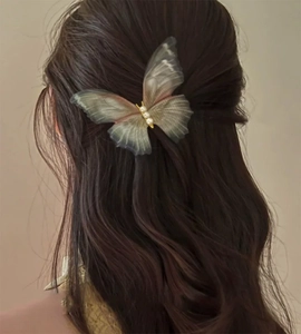 Gros plan sur la barrette papillon en tulle dégradé avec perles sur cheveux ondulés