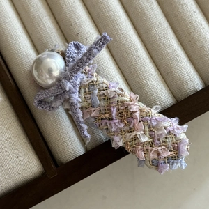 Close-up of pink woven bow hair clip with white pearl detail and purple lace accent