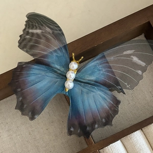 Pince à cheveux papillon élégante avec ailes en tulle bleu et perles sur base dorée