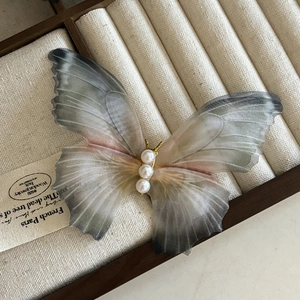 Vue détaillée d'une pince papillon avec des ailes en tulle et des perles blanches