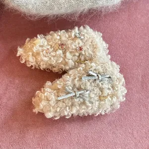 Barrettes en peluche crème avec strass colorés et nœuds argentés sur fond rose
