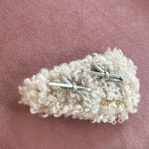 Barrette à cheveux en peluche beige avec nœuds argentés sur fond en velours rose