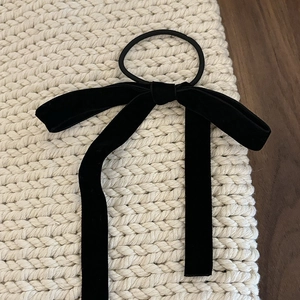 Macro shot of long black velvet ribbon bow hair tie on textured knitted background