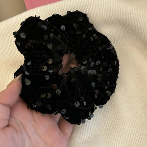 Nahaufnahme von schwarzem Samt-Haargummi mit glitzernden Pailletten auf Strickstoff