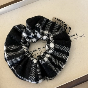 Classic black and white checkered fabric scrunchie with a soft texture and a beige woven label