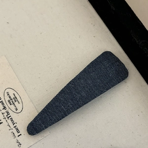Close-up of navy blue denim duckbill clip with white polka dots and texture