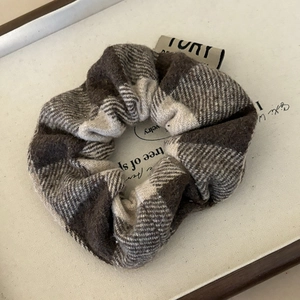 Close-up of retro plaid scrunchie with thick wool fabric and brand logo tag