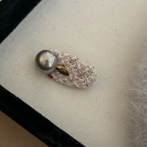 Elegant tweed hair clip with side pearl and Love engraving on a beige background