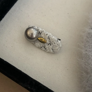 Detailed macro of a tweed hair clip with gold Love charm and grey pearl beads
