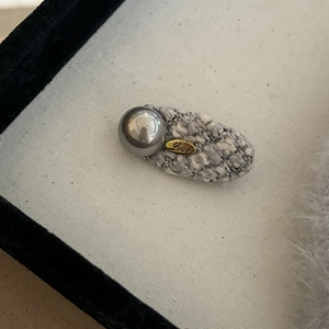 Detail of grey tweed hair clip featuring a silver mirror ball and a gold Love engraved plate