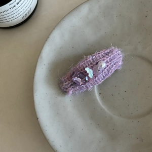 Détail de pince à cheveux tricotée lavande avec pierre violette, perle et petit papillon