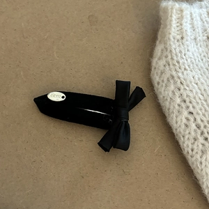 Close-up of black velvet hair clip featuring a satin bow and silver Lucky metal tag
