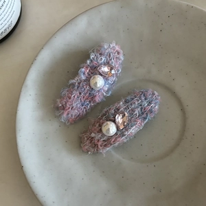 Détail de barrettes à cheveux en tweed avec perles et cristaux dans un plat décoratif
