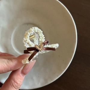 Détail d'une mini pince à cheveux avec nœud marron et bouton en bois en forme de cœur