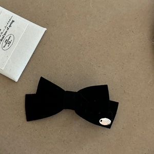 Close-up of black velvet bow hair clip featuring a silver metal plate with LUCKY engraving