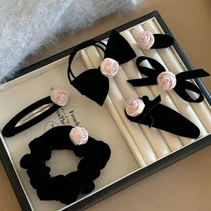 Vue détaillée de pinces à cheveux rose et nœuds en velours noir sur un plateau à bijoux
