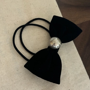 Détail d'un chouchou noeud en velours noir élégant avec une perle en métal argenté poli