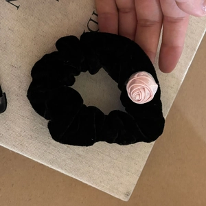 Détail d'un chouchou en velours noir orné d'une délicate rose en satin rose fait main